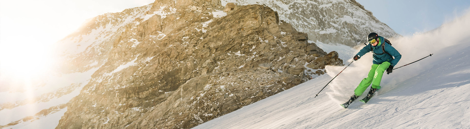 Skier going down a snow covered hill with skis & poles